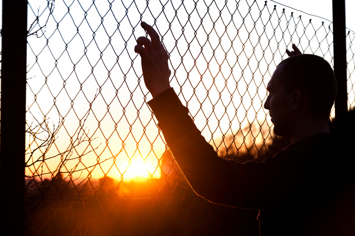 silhouette of a man behind the fence