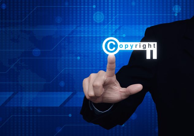 Businessman pressing copyright key icon over digital world map