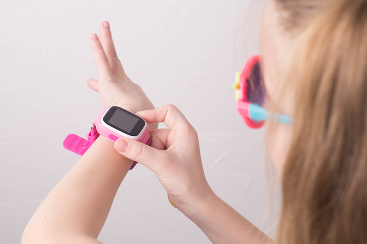 a girl wearing pink glasses uses a smartwatch