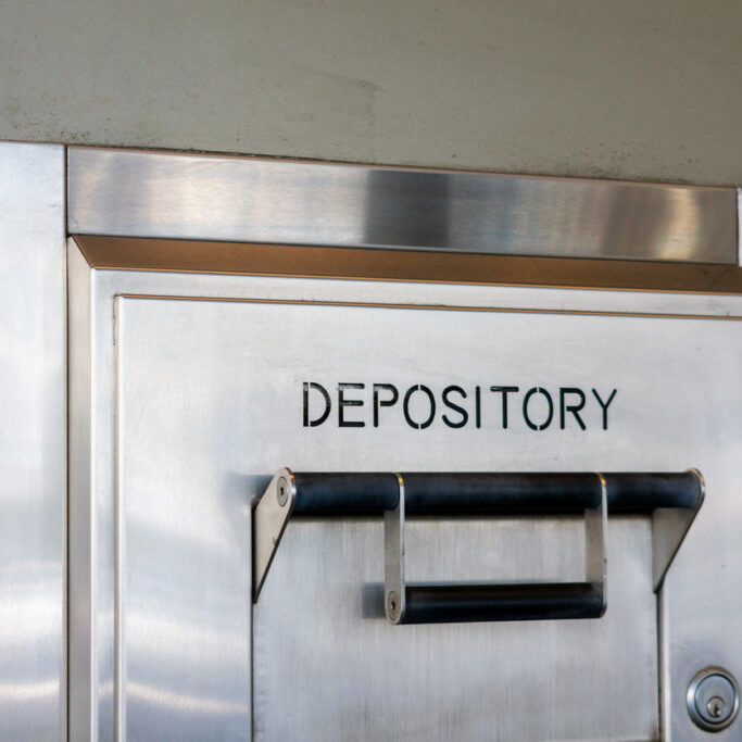 Depository sign on an exterior secured bank drop box attached to the wall of a bank building