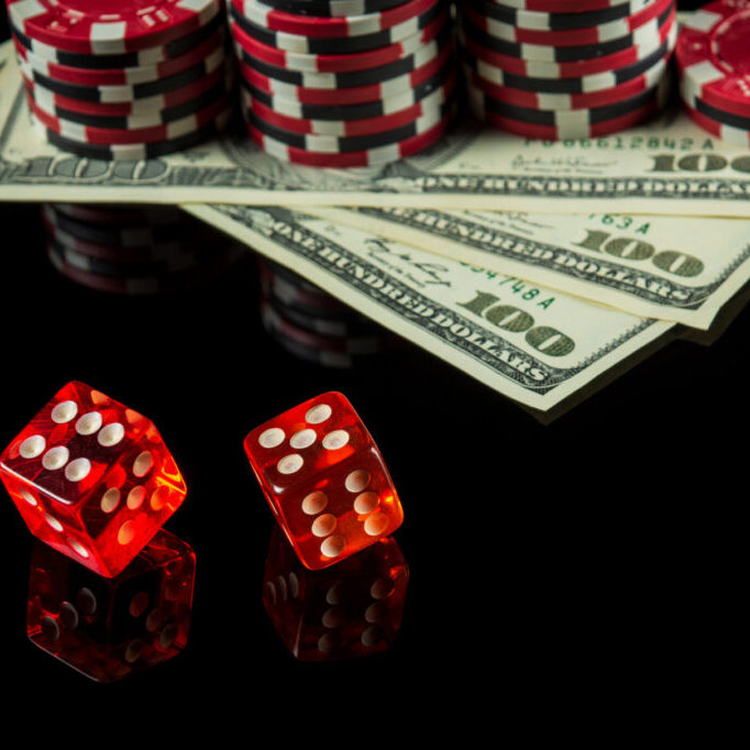 Poker dice with winning combination of eleven on black table and chips with dolars in the background