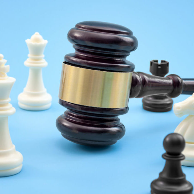 Strategic lawsuit settlement, develop legal strategy and planning court challenge concept with judge gavel and chess pieces isolated on blue background