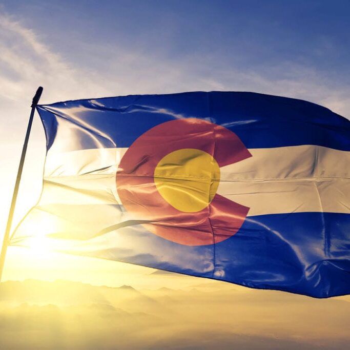Colorado state of United States flag on flagpole textile cloth fabric waving on the top sunrise mist fog
