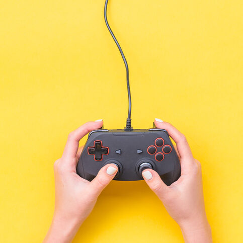 Hands Holding Gamepad. Black joysticks on yellow background. Computer game competition. Gaming concept. Place for text. Flat lay, top view
