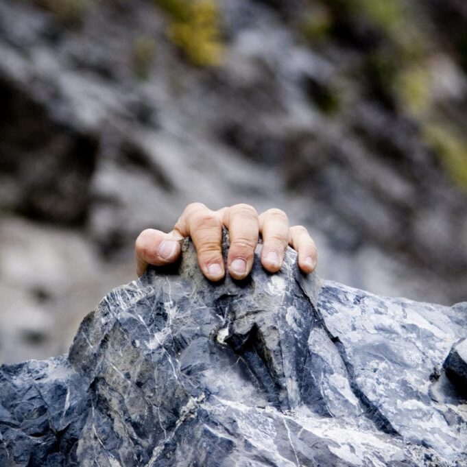A climbers hand grips a rock ledge.