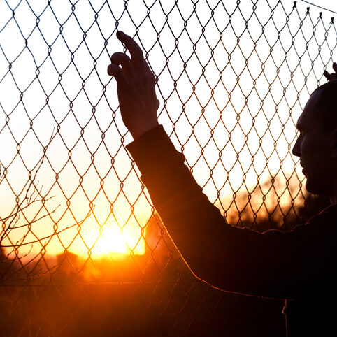 silhouette of a man behind the fence