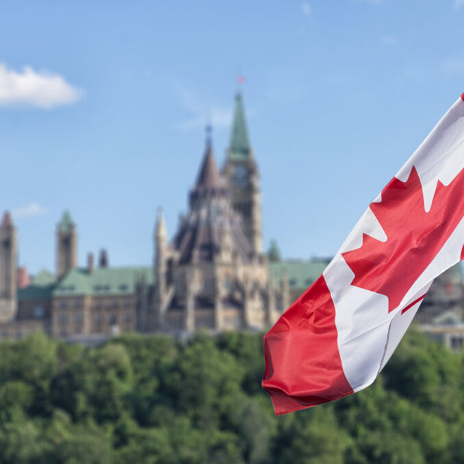 Canadian flag waving with Parliament Buildings hill and Library in the background