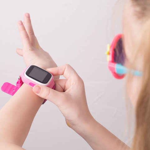 a girl wearing pink glasses uses a smartwatch