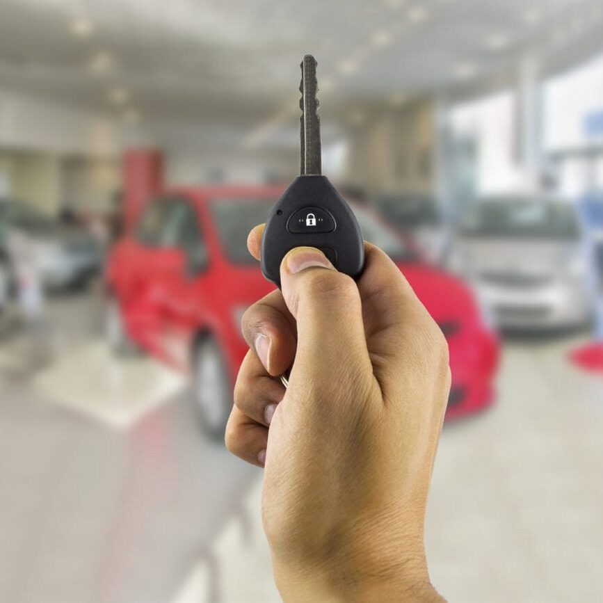 man holding a car key with remote in the concessionaire