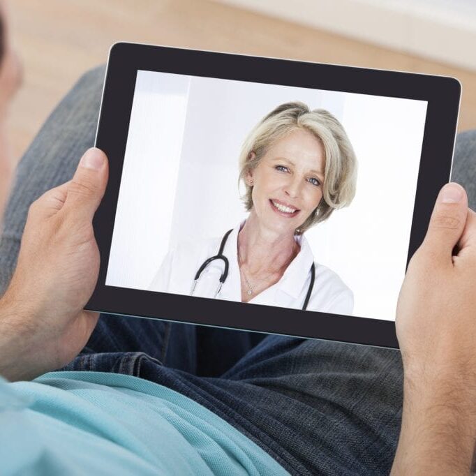 Man having video chat with female doctor on digital tablet at home
