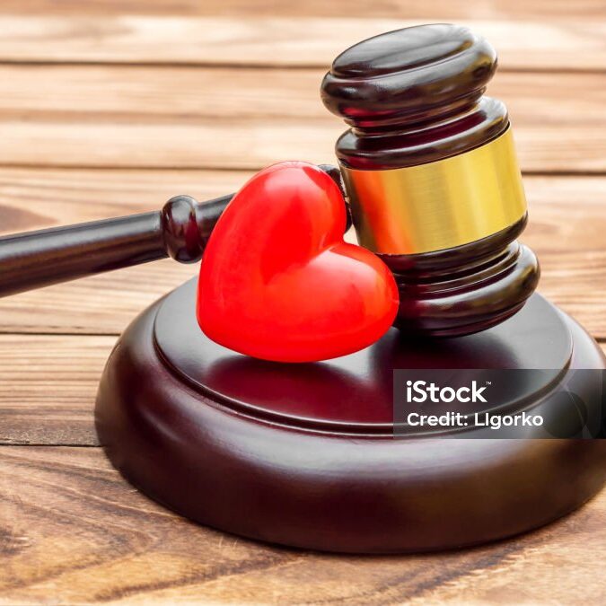 Gavel with red heart on wooden table. Close up.
